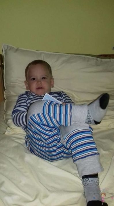 Babyandkidfashion, babaruhák olcsón, kisfiú fekszik az ágyon, az általunk készített babaruhában, kép.