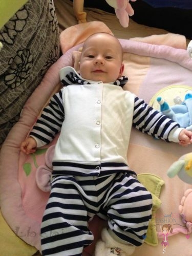 Babyandkidfashion, kisbaba fekszik a kiságyban, az általunk készített ruhában, kép.