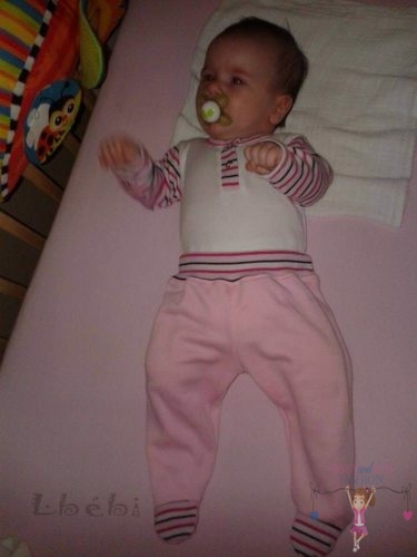 Babyandkidfashion, kislány baba fekszik az ágyon, általunk készített ruhában, kép.