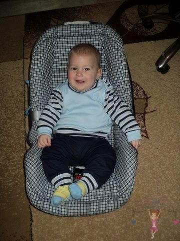 Babyandkidfashion, aranyos kisfiú ül az gyerekülésben, az általunk készített babaruhában, kép.