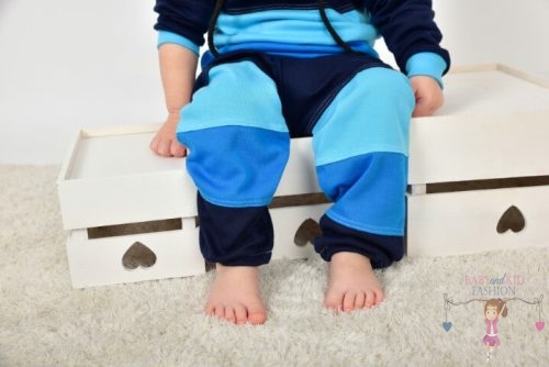 Ládán csücsülő kisfiú, kék színű variációkkal lévő nadrágban, kép.