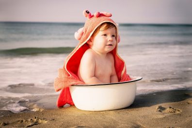 babaruhák mosása, kisbaba ül egy lavorban, mögötte a tenger.