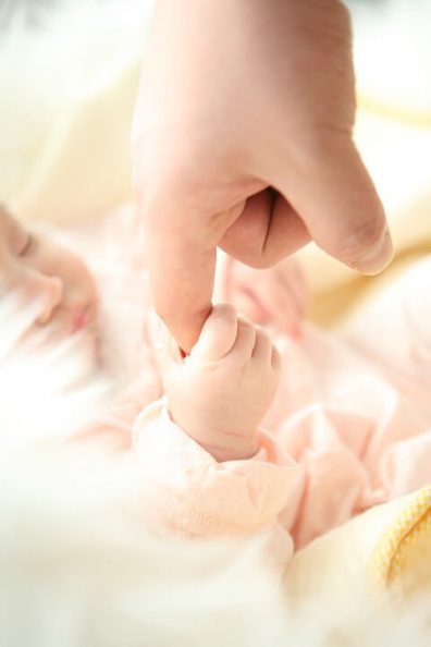 Első nap a babával. Az újszülött kis kezével szorítja az édesanyja ujját, kép.