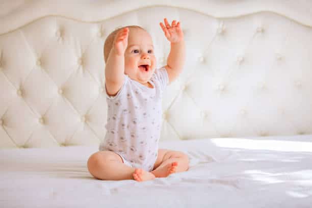 Egyedi babyruhák: kisbaba nyújtózkodik egy gyönyörű plüss fotelben