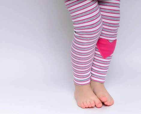 kislány áll pink csíkos leggingsben, pink szívvel, kép.